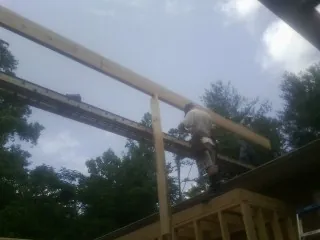 Carpenter setting a ridge beam over a new addition frame — Ice Dam Removal by Roofing Brothers in Montague